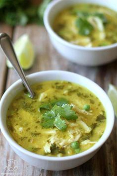 two white bowls filled with soup and garnished with cilantro, limes, and parsley