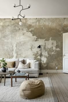 a living room with a couch, table and lamp on the wall in front of it