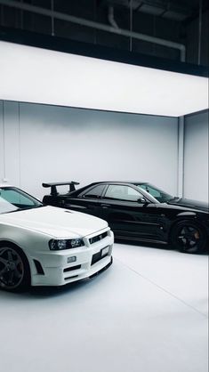 two cars parked in a white room with no one around them and the other car behind them