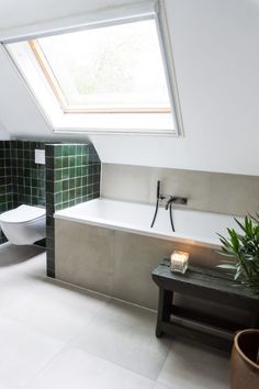 a bathroom with a skylight above the toilet and bathtub, next to a bench