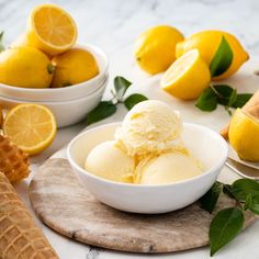 two bowls filled with ice cream next to lemons and waffle cones on a table