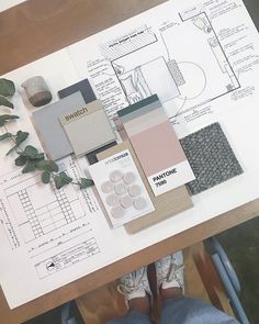 a person sitting at a table in front of some design drawings and paint swatches