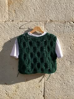 a green knitted sweater hanging on a wall