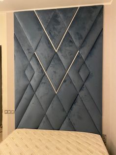 an upholstered headboard in the corner of a room with a white bed