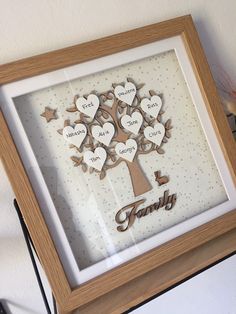 a family tree with hearts and stars is shown in a wooden frame on the wall