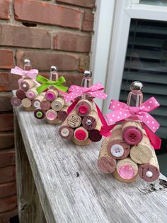 three wine corks with bows and buttons on them sitting on a wooden table in front of a brick wall