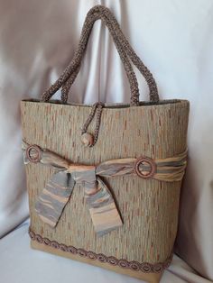 This particular bag is made with upholstery fabric on an eco-leather base. The point of union between the leather and the fabric is hidden by a series of small rings, covered with cotton thread. Four larger loops, lined with the same cotton, hold a silk ribbon that surrounds the bag and is tied with a ribbon at the front of the bag. The handles are made with a cord covered in crocheted chenille; their length allows the bag to be worn by hand or on the shoulder. The closure is formed by a button Rectangular Bags With Loop Closure For Everyday Use, Everyday Rectangular Bag With Loop Closure, Fabric Shopping Bag With Adjustable Strap, Fabric Shoulder Bag With Adjustable Strap For Shopping, Elegant Shoulder Bag With Loop Closure For Daily Use, Elegant Daily Use Bag With Loop Closure, Brown Fabric Tote Shoulder Bag, Elegant Woven Tote Shoulder Bag, Rectangular Fabric Bag With Adjustable Strap