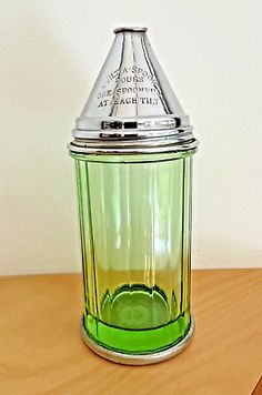 a green glass jar sitting on top of a wooden table