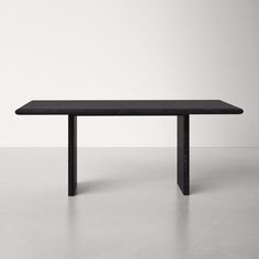 a black table sitting on top of a cement floor next to a white wall in an empty room