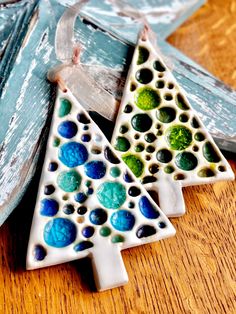 two ceramic christmas trees sitting on top of a wooden table