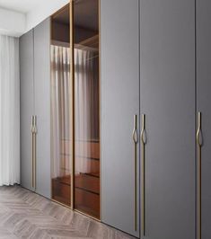 an empty room with grey cabinets and gold handles on the doors, along with white curtains