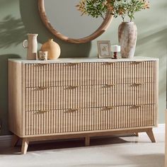 a wooden dresser sitting next to a mirror and vase