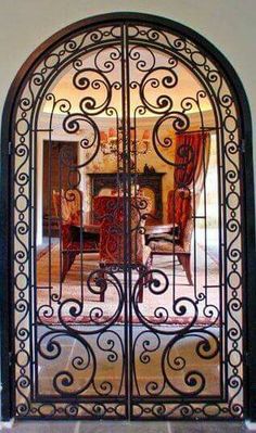 an ornate iron door is open to the dining room