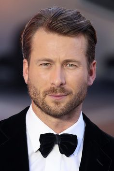 a close up of a person wearing a suit and bow tie