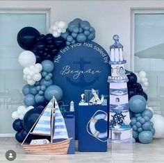 a blue and white balloon arch with sailboat, lighthouse and other items in front of it