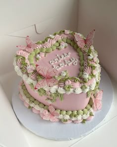 a pink and green birthday cake with butterflies on it's top, sitting in a box