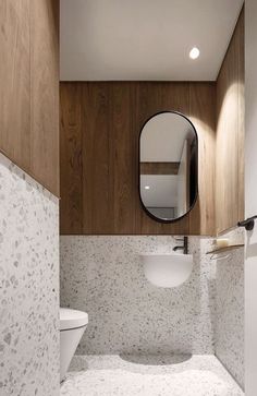 a bathroom with a sink, mirror and toilet in it's corner area next to a wood paneled wall