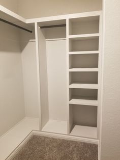 an empty walk in closet with white shelves and carpeted flooring on the side