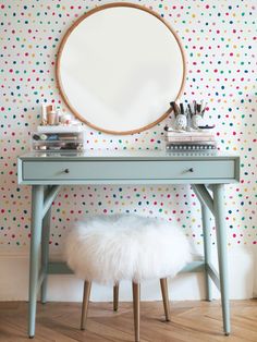 a blue desk with a round mirror above it