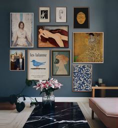 a living room with blue walls and pictures on the wall, including flowers in a vase