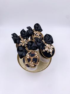 black and gold decorated cookies sitting on a plate with bowknots around them