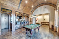 a pool table in the middle of a room with wood flooring and walls that have been built into it