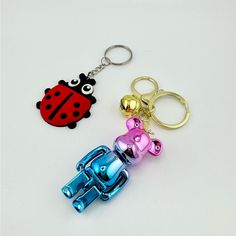 two key chains with ladybug and car charms attached to them on a white surface