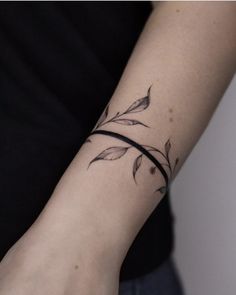 a person with a wrist tattoo that has leaves on it and a thin band around the wrist