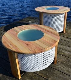 two round tables sitting on top of a wooden dock next to the ocean with blue water