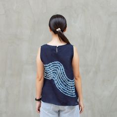 a woman standing in front of a wall wearing a blue shirt with white waves on it