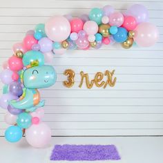 a balloon arch that says 3 eleven with balloons surrounding it and a dinosaur balloon in the center