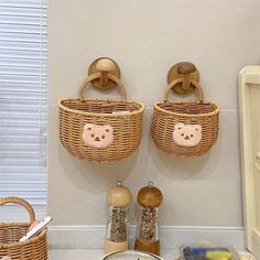 two wicker baskets are hanging on the wall above a counter with spices and other kitchen items