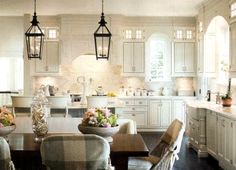 a kitchen filled with lots of white cabinets and counter top space next to a dining room table