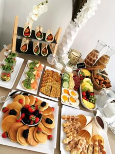 a table topped with lots of plates and trays filled with different types of food