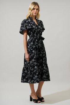 The Patricia Floral Noelle Split Neck Poplin Tiered Midi Dress is an evening favorite! A ruffled split neck tops an A line, tiered silhouette. Short sleeves frame the breezy, poplin midi dress. Side seam pockets are added for convenience. Pair it with gold accessories and woven mules for a fresh look.- Poplin- Mid length- Split neckline- Tiered- Color: Black WhiteSize + Fit - Model is 5'11" and wearing size XS- Measurements taken from size S - Chest: 19"- Length: 48" Fabric Self: 100% Cotton Sty Elegant Tiered Cotton Midi Dress, Black Tiered Ruffle Dress For Spring, Black Tiered Dress With Ruffle Hem For Spring, Black Tiered Dress For Spring, Elegant Black Tiered Dress For Spring, Spring Workwear Midi Dress With Ruffles, Elegant Short Sleeve Tiered Spring Dress, Black Fitted Tiered Dress For Spring, Elegant Black Tiered Summer Dress