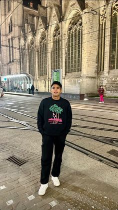 a man standing in the middle of a street next to a train track and an old building