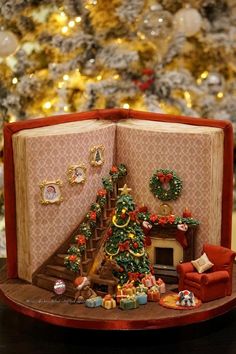 a miniature christmas tree is in the corner of an open book with decorations on it