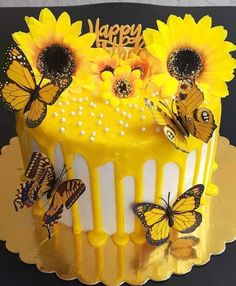 a yellow cake with sunflowers and butterflies on it's icing is sitting on a table