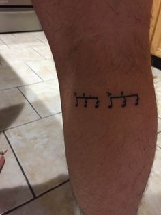 a man's foot with hebrew symbols tattooed on the lower part of his leg