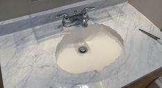 a bathroom sink with white marble counter top and chrome faucet on the side