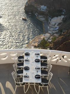 the table is set with black and white place settings on the balcony overlooking the ocean