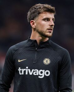 a soccer player is standing on the field wearing a black uniform and looking off into the distance