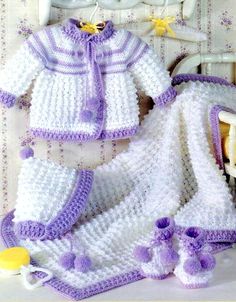 there is a crocheted baby outfit and booties on the bed next to it