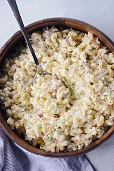 a wooden bowl filled with macaroni salad on top of a white tablecloth