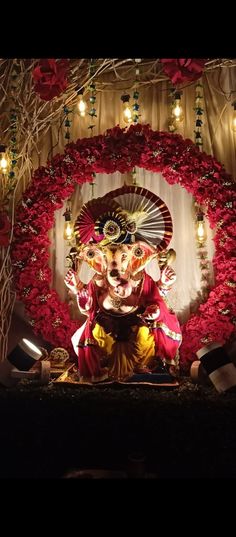 an idol is displayed in front of a backdrop with red flowers and lite - up candles