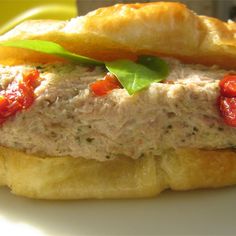 a close up of a sandwich with meat and tomatoes on it sitting on a plate