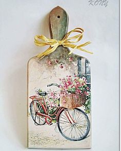 a tag with a painting of a bicycle and flowers tied to the front, hanging on a wall