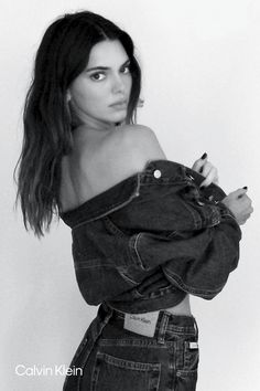 a black and white photo of a woman in denim clothes with her arms crossed looking at the camera