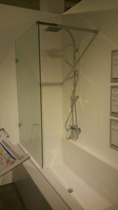 a white bath tub sitting next to a toilet under a shower head mounted on a wall