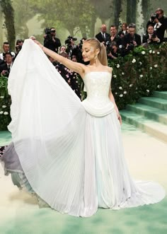 a woman in a white gown holding up a dress